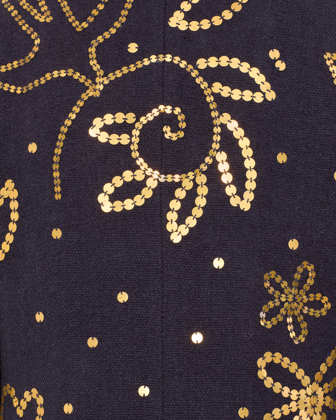Close-up of the Petunia Midnight Coin Coat, a dark hand-embellished piece with gold sequin floral and swirl embroidery, showcasing the garment's intricate artisan detailing.