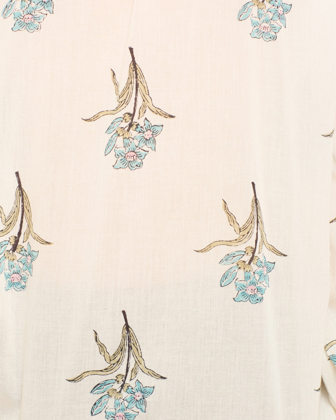 The Poet Sky Mist Flower Blouse is a cream-colored cotton voile shirt, hand-block-printed with small blue flowers and brown leaves in a scattered pattern.