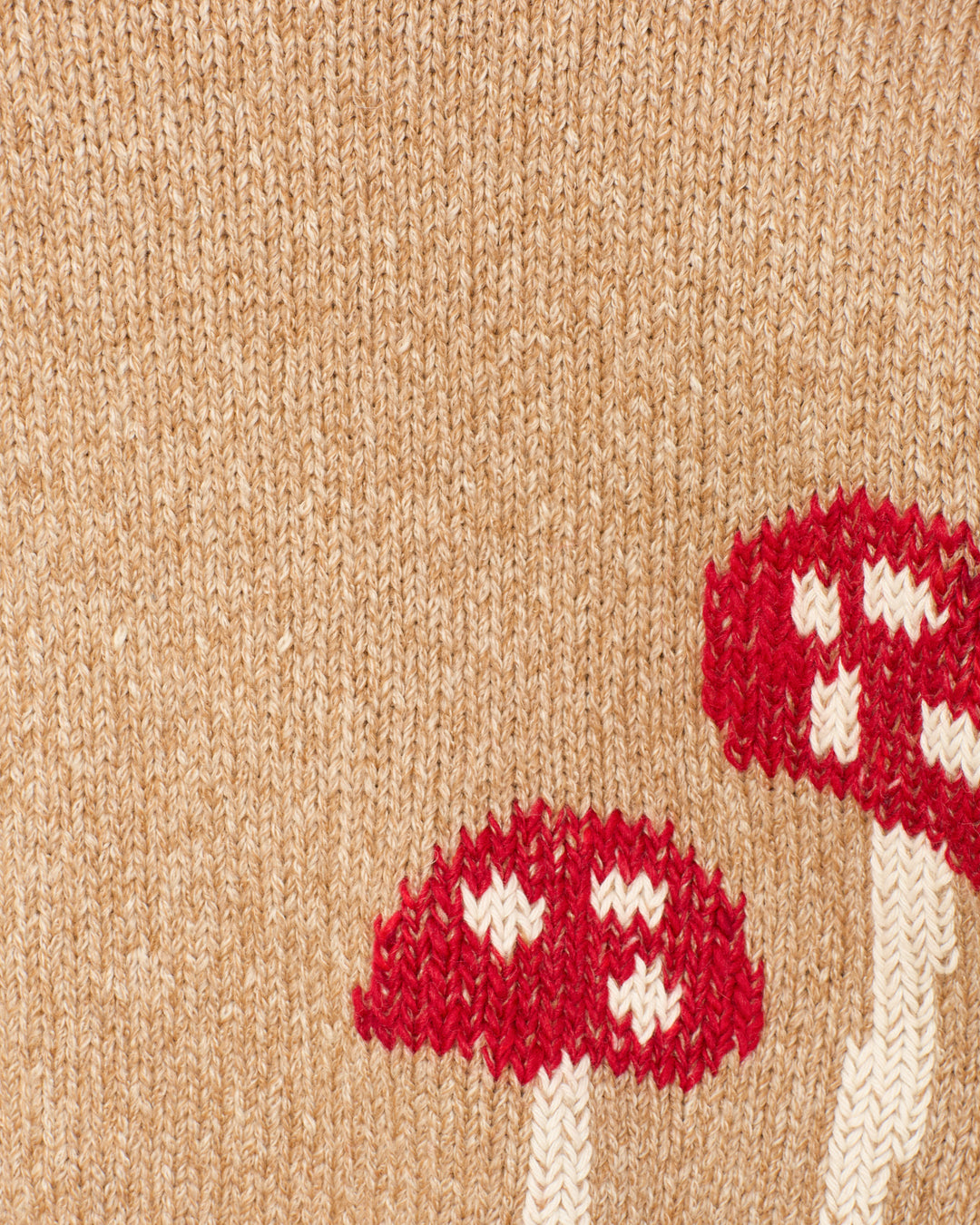Close-up of the Sammi Mushroom Knit Cardigan in beige, showcasing a red and white toadstool motif on the bottom right corner.