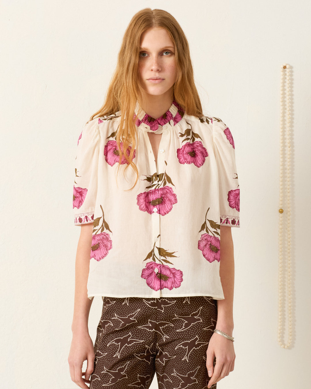 A woman in the Winn Fuchsia Poppy Shirt, crafted from hand-block-printed cotton voile with a delicate poppy motif.