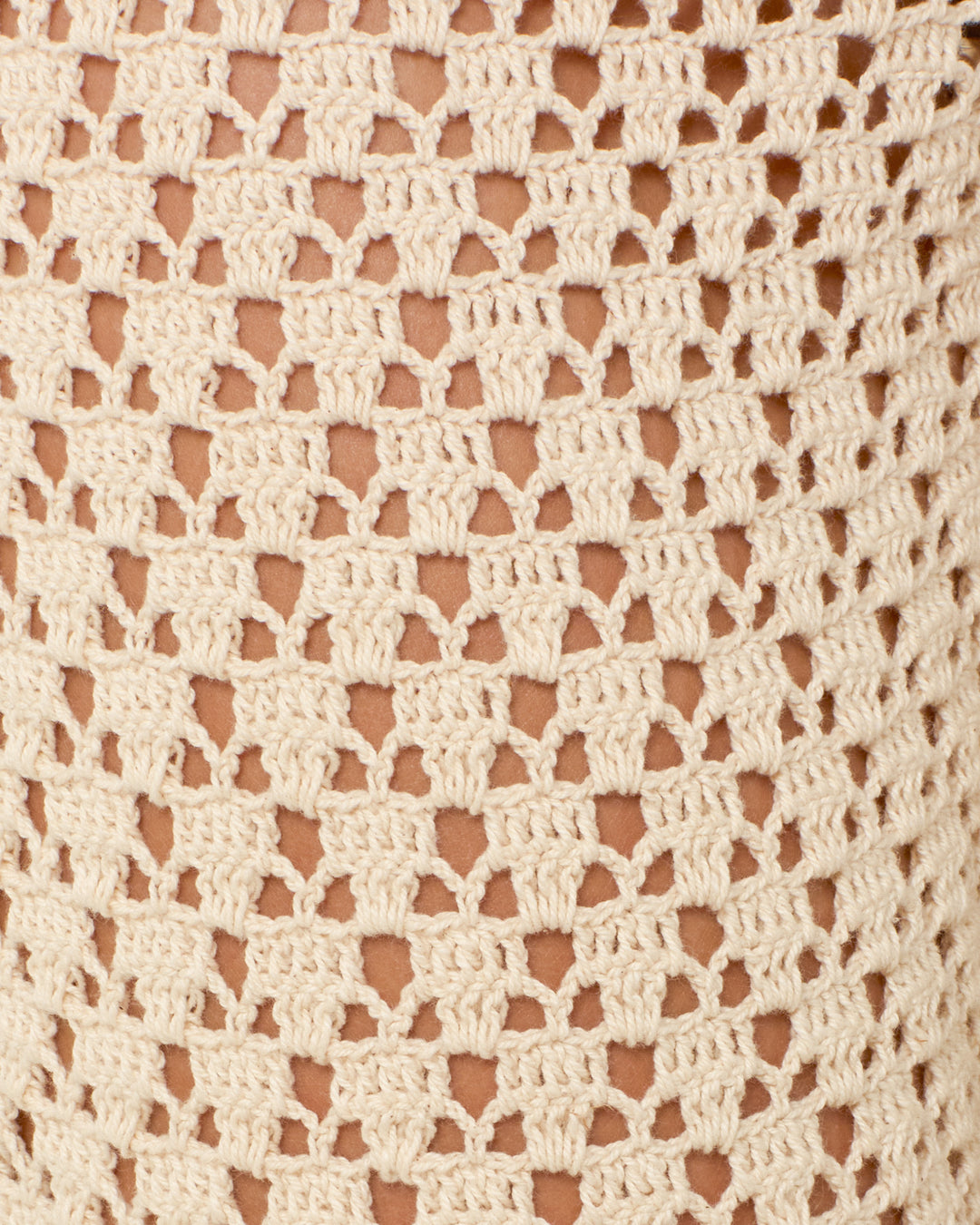 Close-up of the Aletta Ecru Mandala Pant’s vintage-inspired beige crochet fabric, featuring a repeating geometric pattern with open spaces and textured stitches.