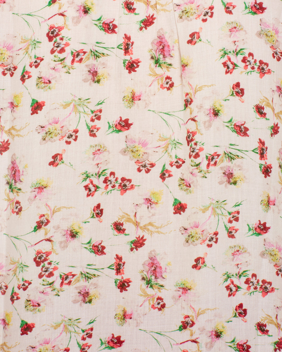 The Artemis Wild Garden Shirt is a light pink modal top with a scattered floral pattern in red, pink, and yellow hues, green leaves, and charming puff sleeves.