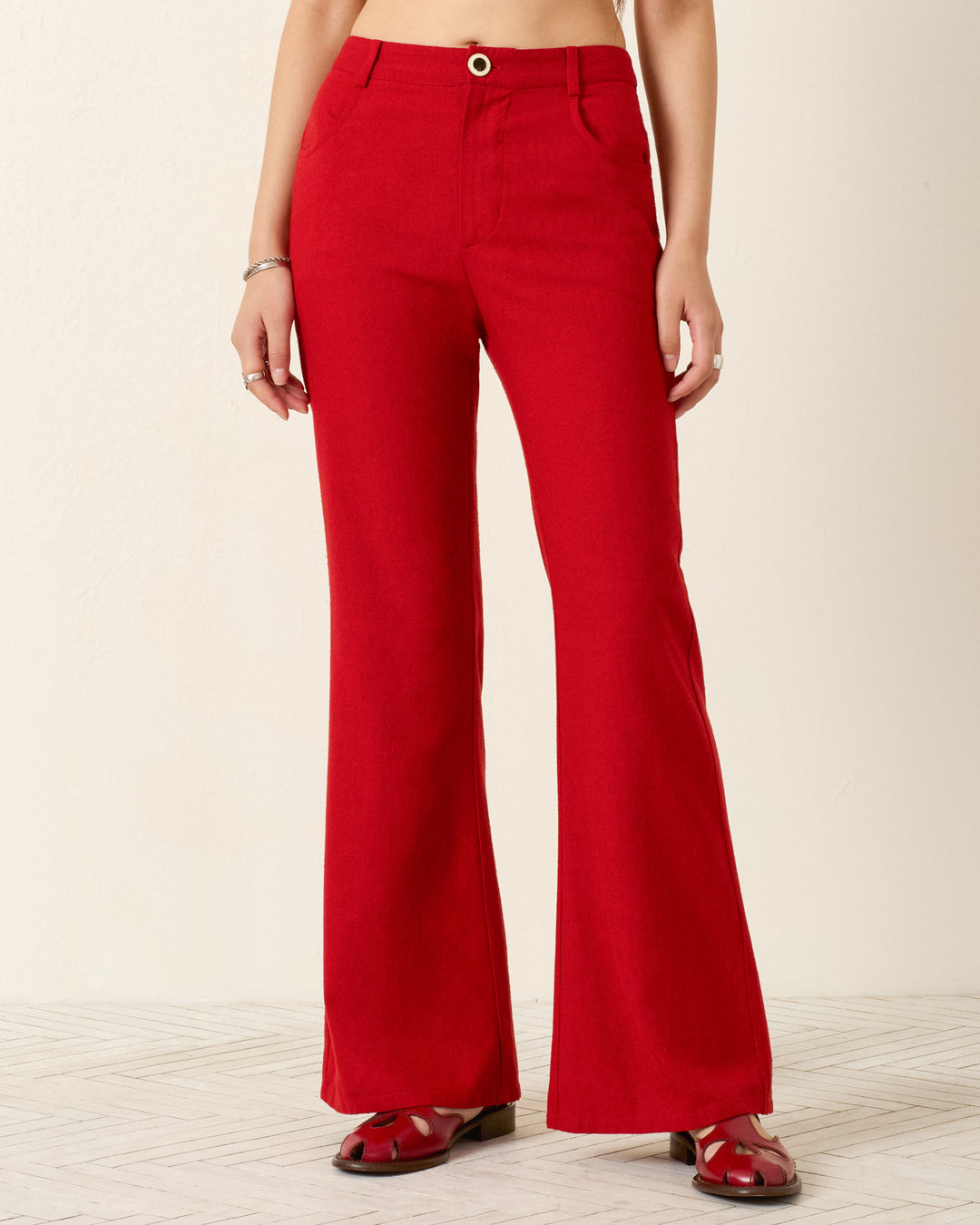 A person is wearing the Bunny Russet Silk Jean, featuring a high waist, slim flared leg, and button closure. Only their lower torso and legs are visible against a plain light background.