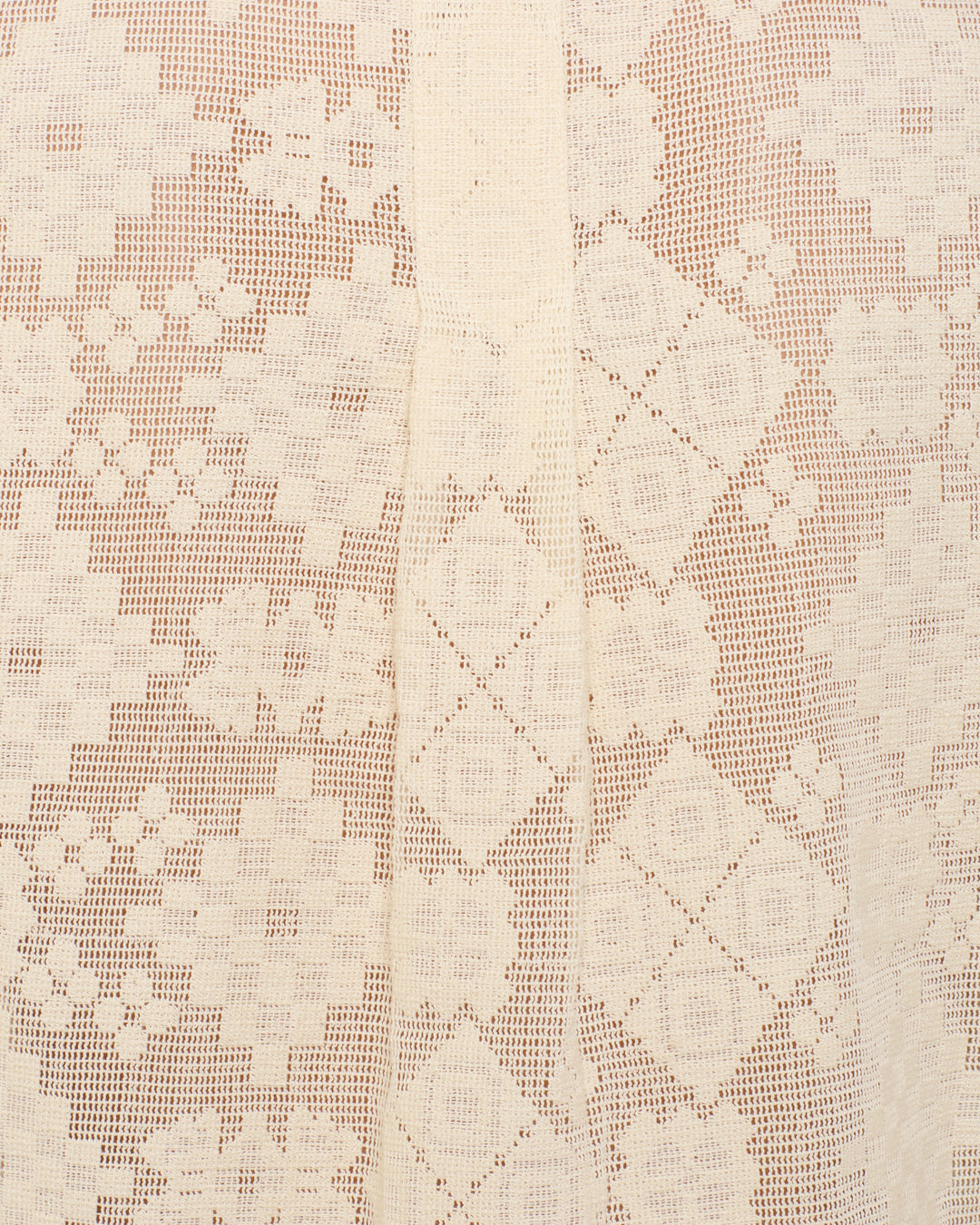 Close-up of the Chance Ecru Tetris Lace Top’s beige cotton fabric, showcasing geometric and floral lace patterns with a vertical center seam.