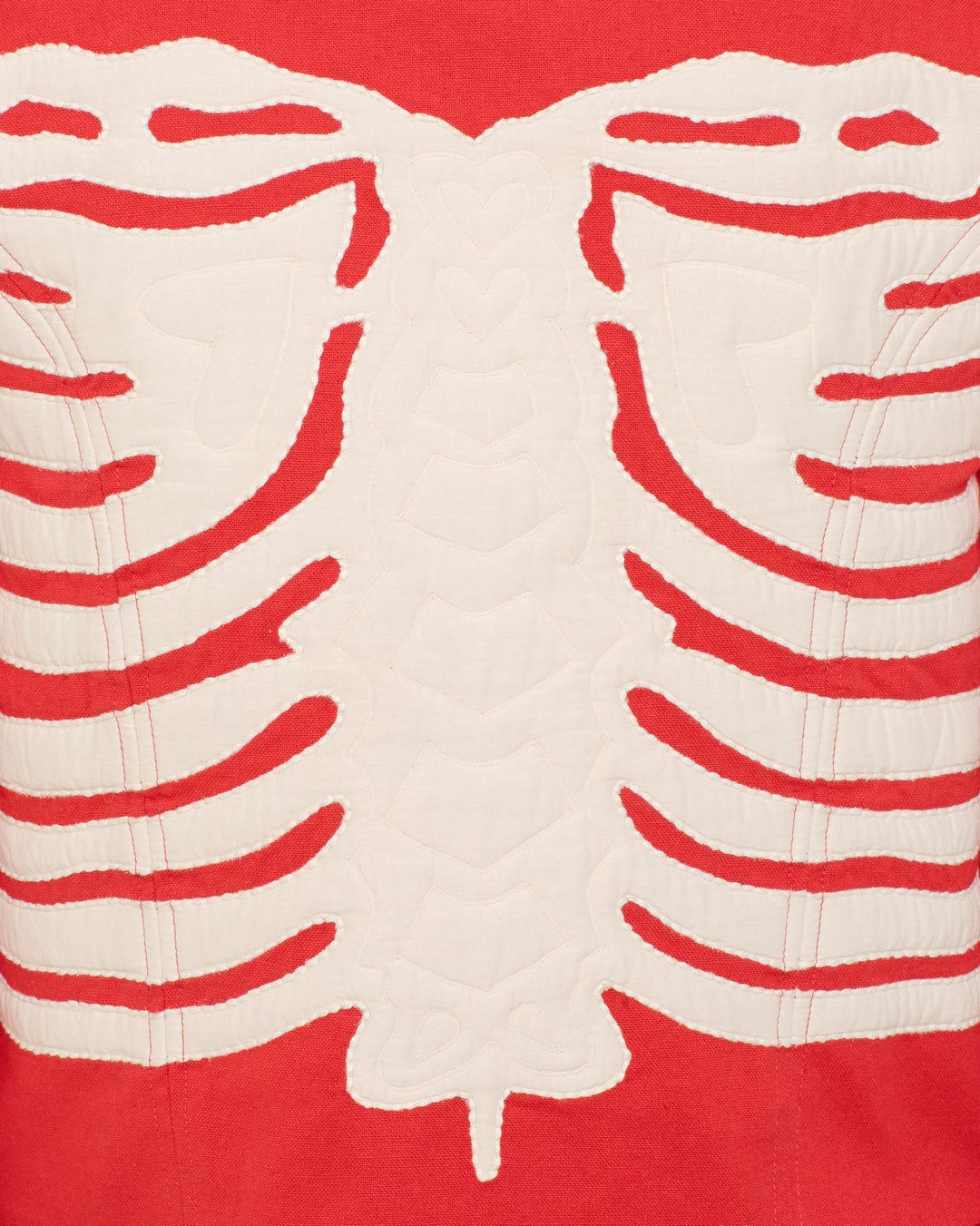 Close-up of the Dorian Ibis Bone Jacket, showcasing its textured cotton fabric in red with a white skeleton motif resembling a stylized human ribcage and spine.