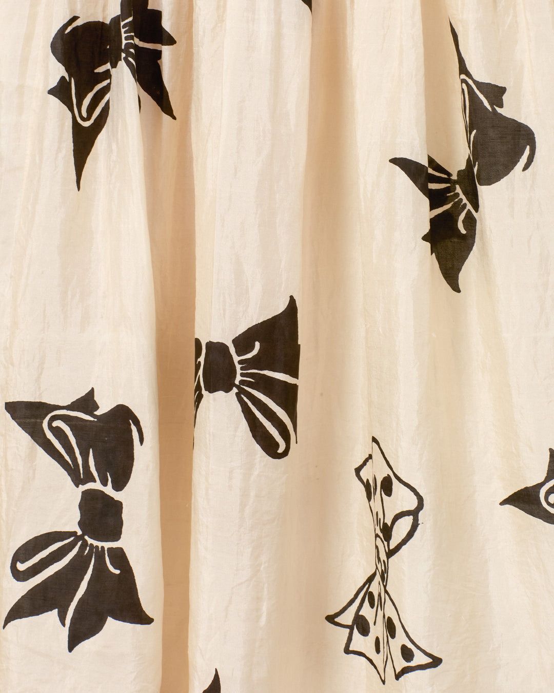 The Ellina Black Tie Silk Dress features cream-colored silk fabric adorned with solid and polka-dotted black bow patterns—ideal for a chic maxi dress and pairs beautifully with cotton lace trim.