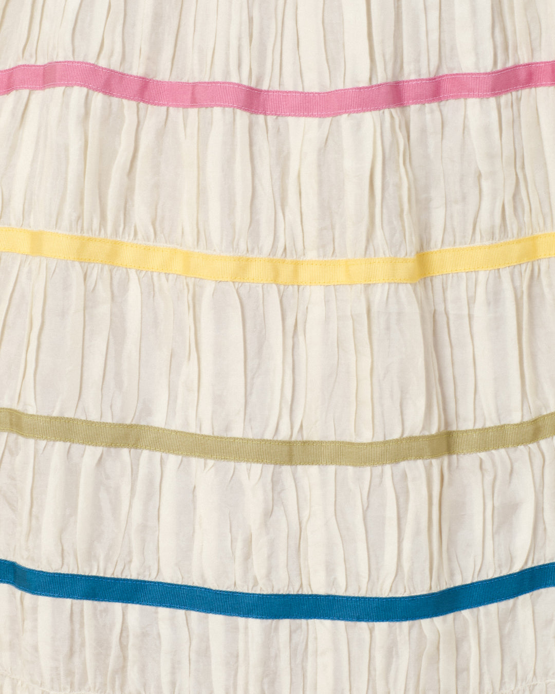 The Emrys Ivory Aurora Dress is a white, hand-loomed silk piece with horizontal pleats and vibrant pink, yellow, olive green, and blue bands for an artisan-inspired look.