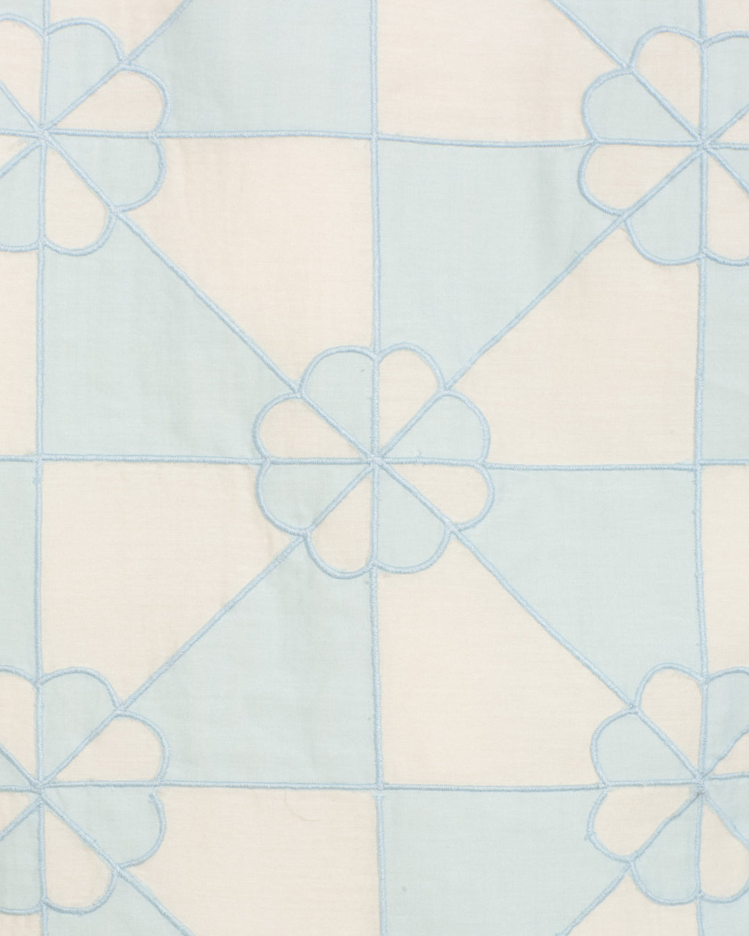 The Jude Sky Jubilee Jacket features a light blue and white geometric fabric with intersecting lines and blue-stitched flower shapes in a mosaic-inspired pattern—ideal for handmade quilted styles.