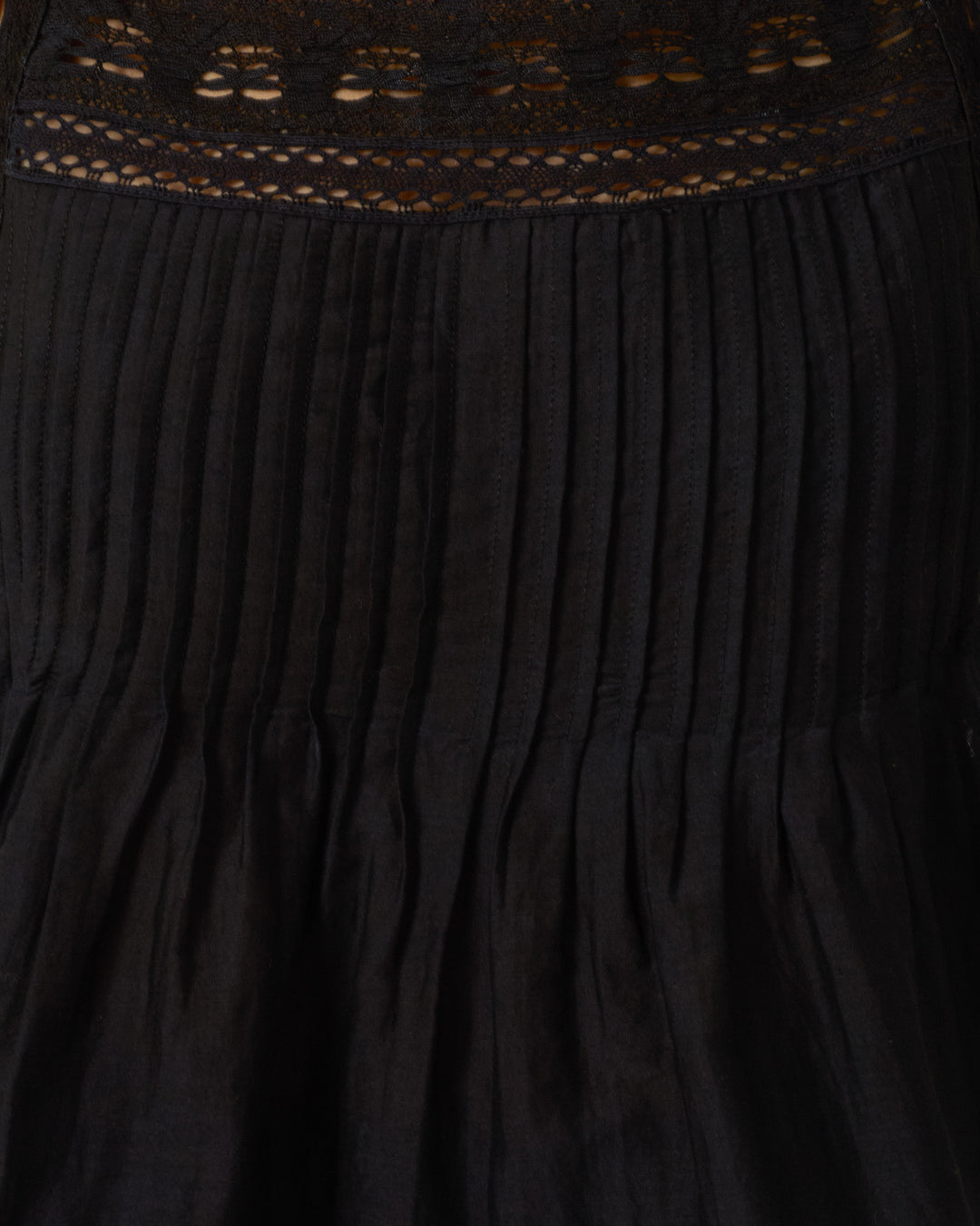 Close-up of the Mimi Onyx Prima Lace Top featuring black pleated fabric with cotton lace and embroidered details along the top edge.