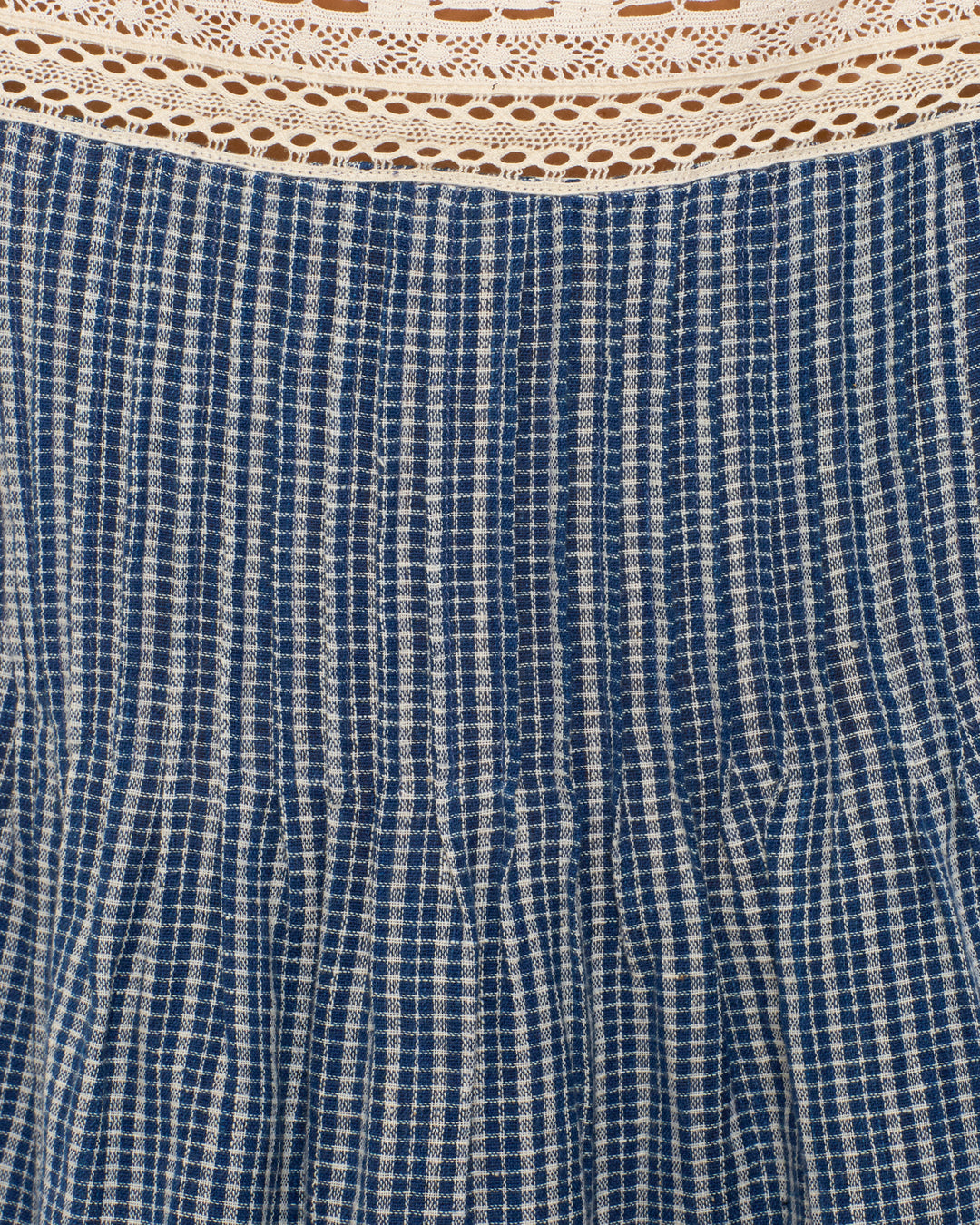 The Mimi Prima Micro Plaid Top features blue and white vertically-striped Khadi cotton with pleats and cream-colored lace trim, creating a charming sleeveless look.