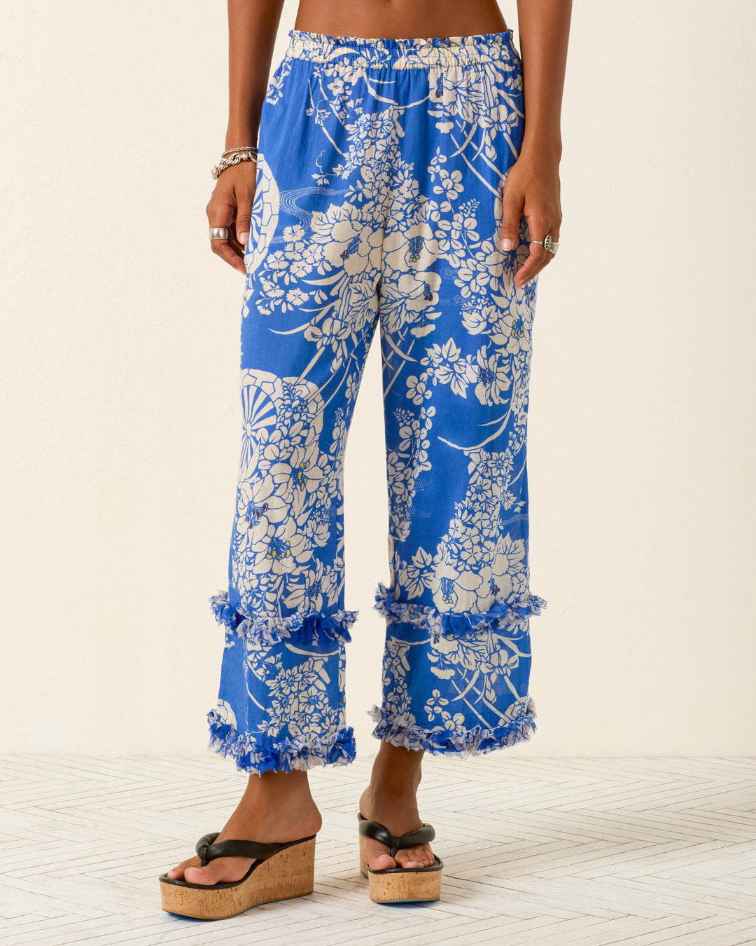 Model wears Otto Royal Spoke Pant, blue hanaguruma motif cotton voile with fringe hem at mid-calf and pajama-style silhouette, paired with black platform sandals.