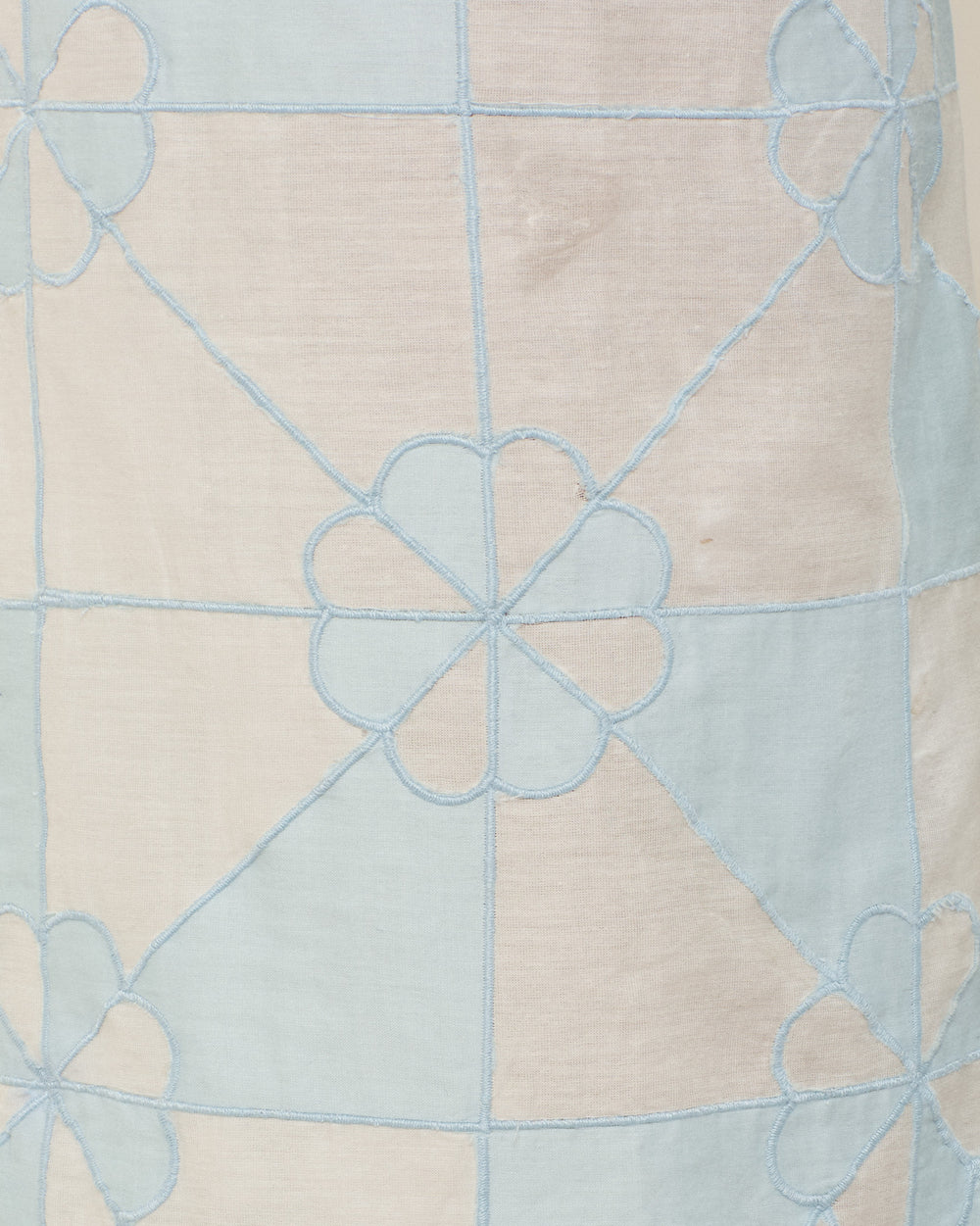 Close-up of the Otto Sky Jubilee Pant fabric, showcasing light blue embroidered flowers and intersecting lines on a pale pastel background, hand-quilted for a unique geometric patchwork look.