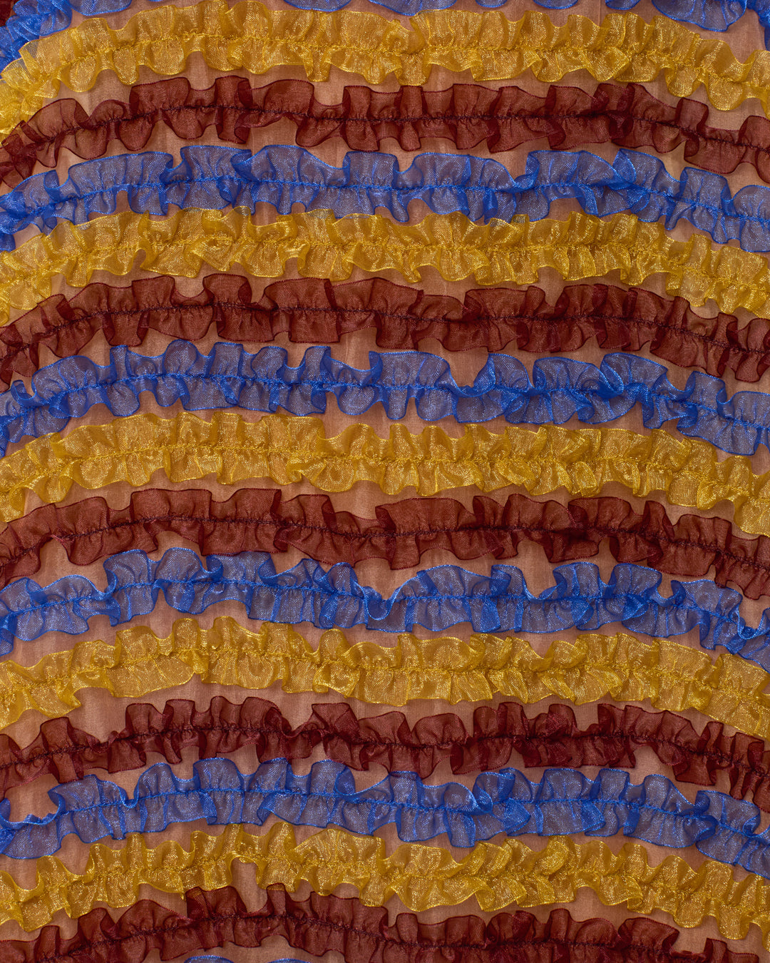 The Soleil Jester Vale Dress features rows of ruffled fabric in blue, yellow, and burgundy, arranged in playful horizontal stripes.