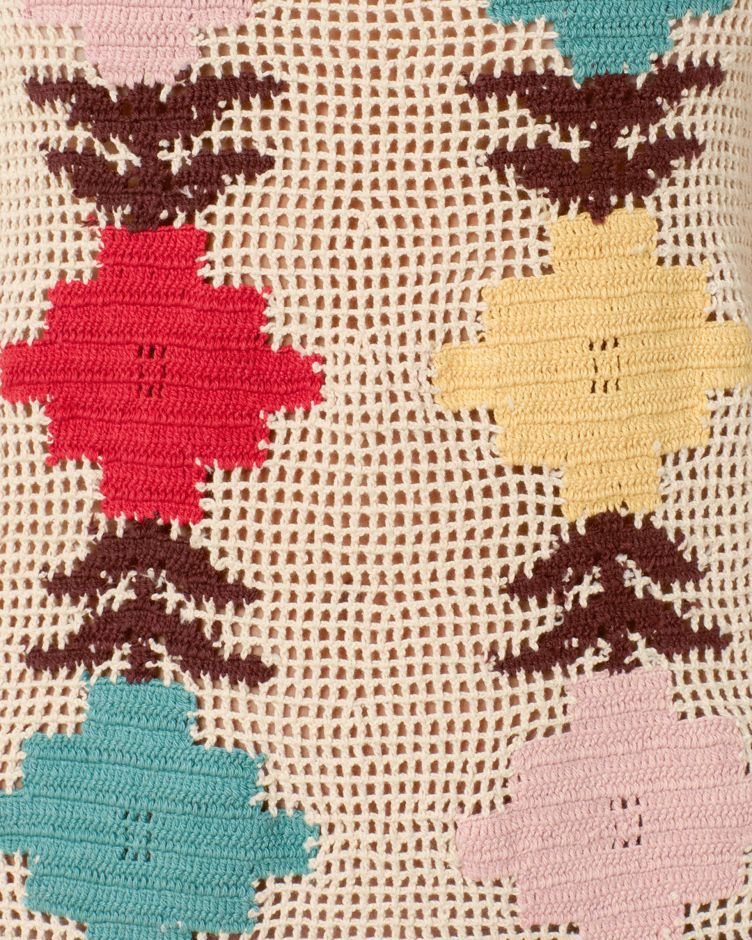 Close-up of the Tyler Daisy Chain Dress, a hand-crocheted tank dress with red, yellow, and blue geometric shapes plus brown accents on a beige open-weave background.