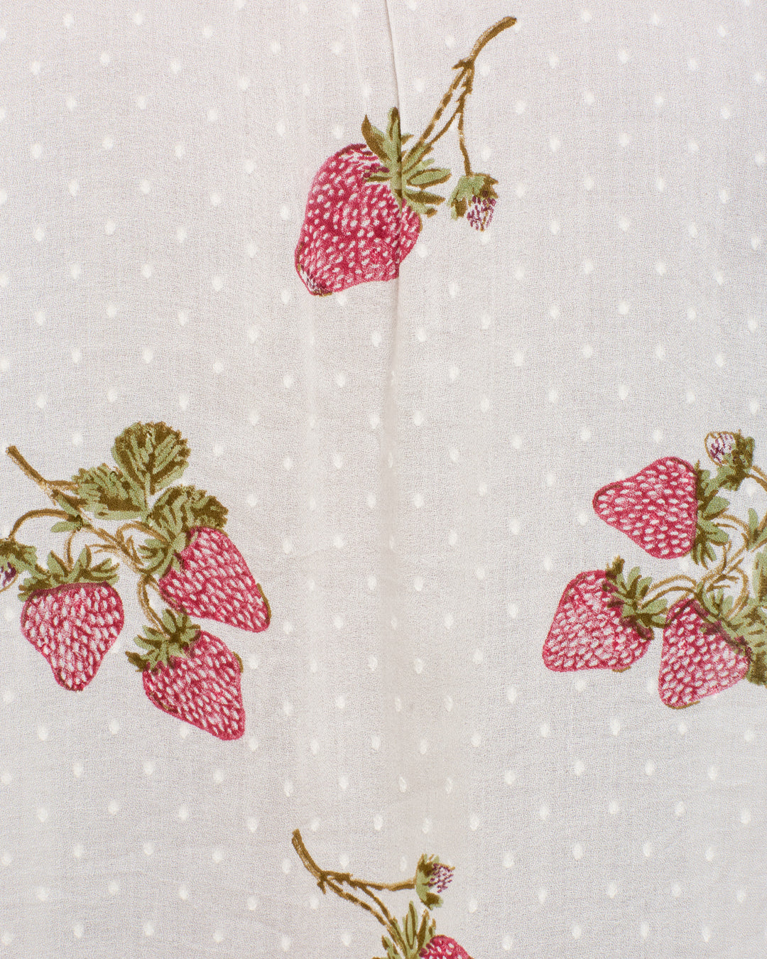 The Winnie Strawberry Dot Shirt features white fabric with small polka dots and embroidered red strawberries with green leaves, creating a charming, playful motif.
