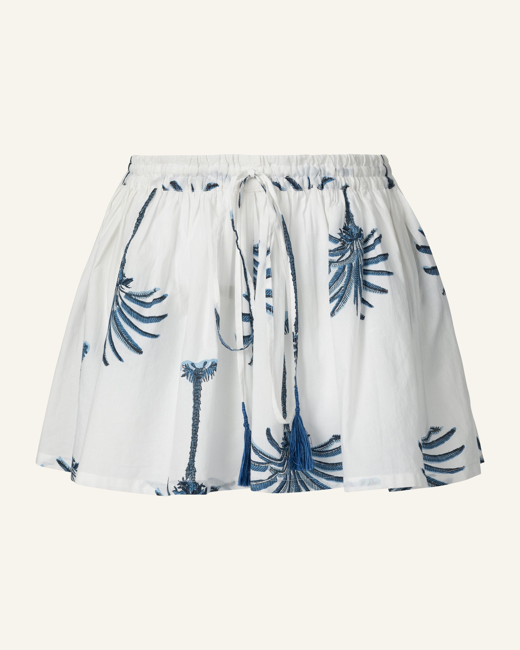 Introducing the Christy Indigo Palm Short: a white mini skirt crafted from hand-printed cotton, showcasing blue palm tree designs. It features a relaxed fit and a convenient drawstring waistband.